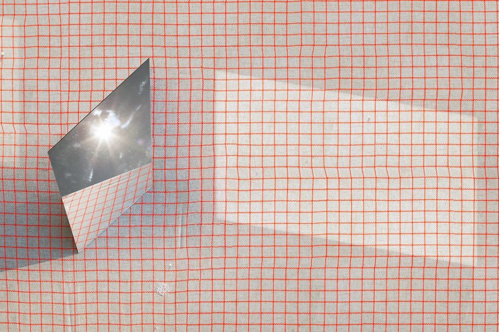 Hero image: mirror sits angled on a grid background, reflecting sun rays onto the grid.