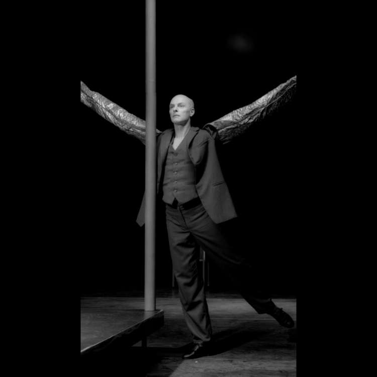 Picture in black and white of Paul-André Fortier dancing beside a tall pole with arms outstretched.