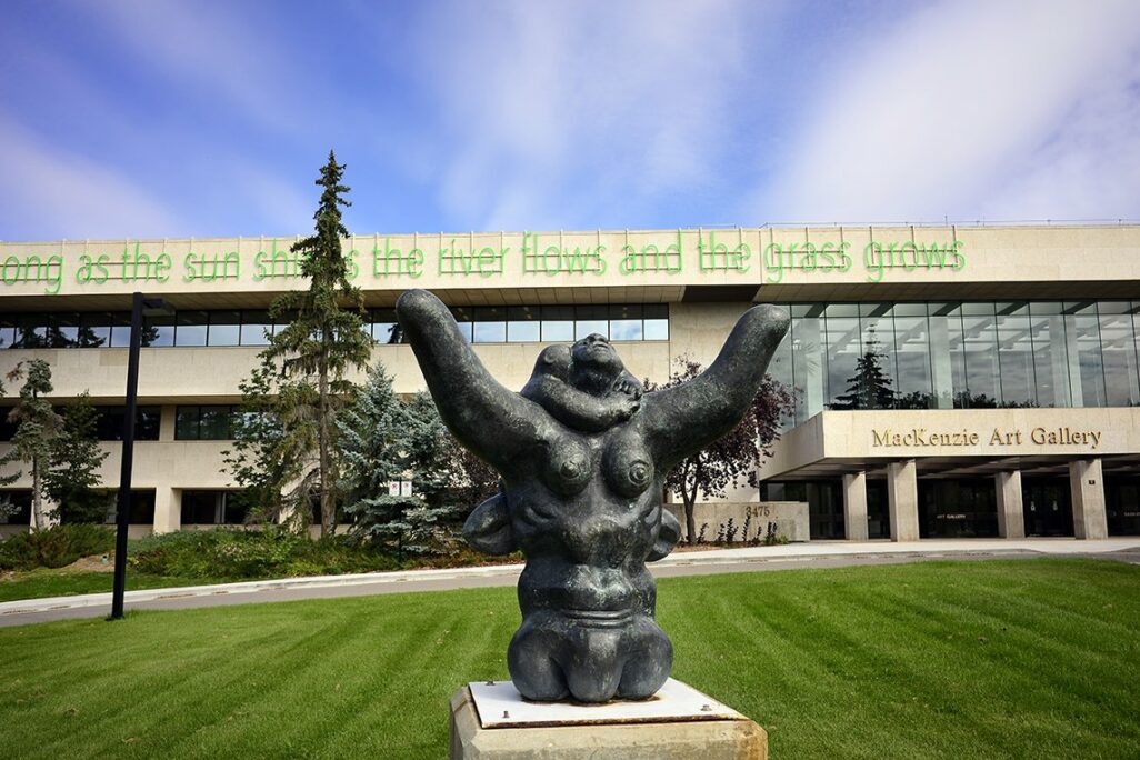 Outside view of the MacKenzie Art Gallery with a sculpture of a woman with her arms raised to the sky in the foreground