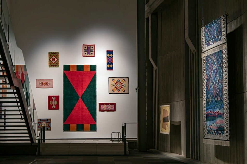 Textile works hung on the wall of a gallery.