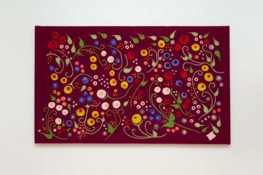 Felted flowers in whimsical and swirly patterns on a large canvas.