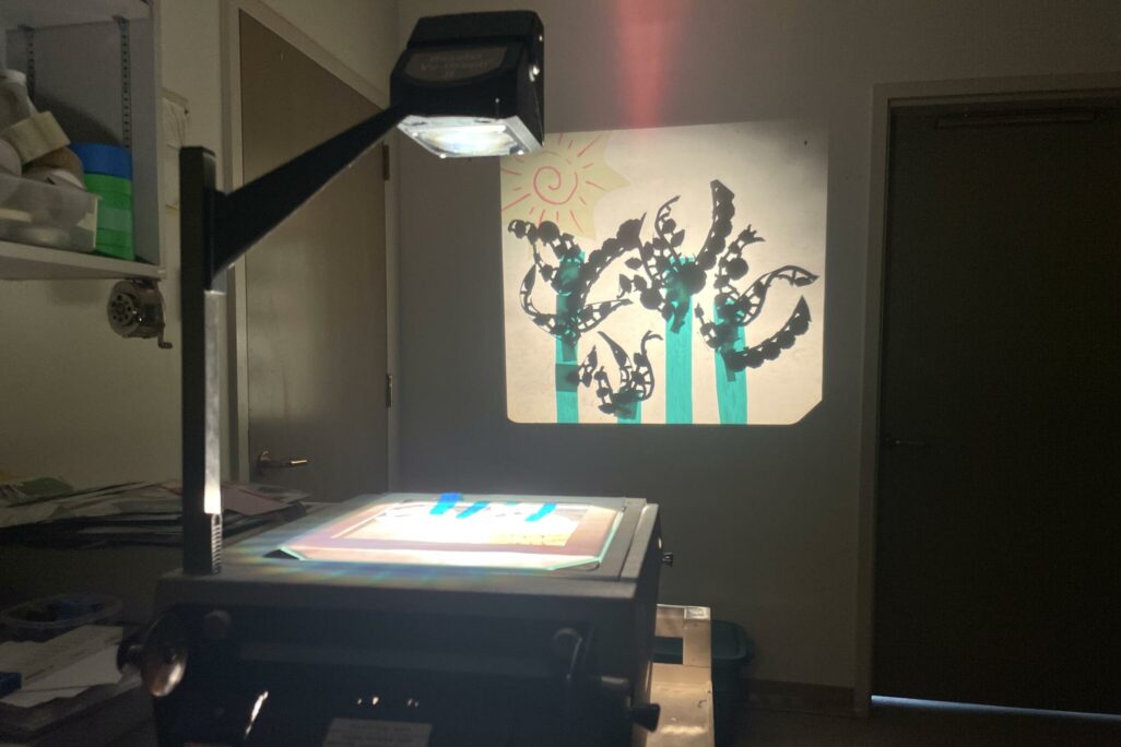The light from the overhead projector casts a display of colourful images creating shadow puppets using transparent cellophane.