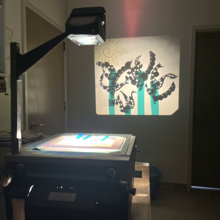 The light from the overhead projector casts a display of colourful images creating shadow puppets using transparent cellophane.